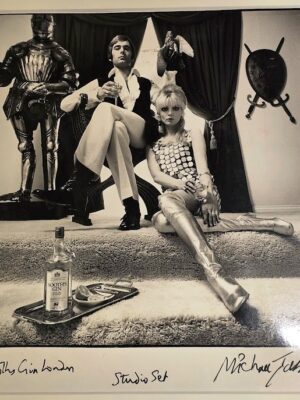 Couple drinking Booths gin next to knight in shining armour and shield by Michael Joseph