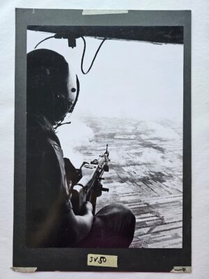 Soldier toting Machine gun from helicopter over Saigon by Michael Joseph