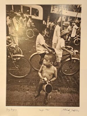 South Vietnam, boy begging in street while world carries on around him by Michael Joseph