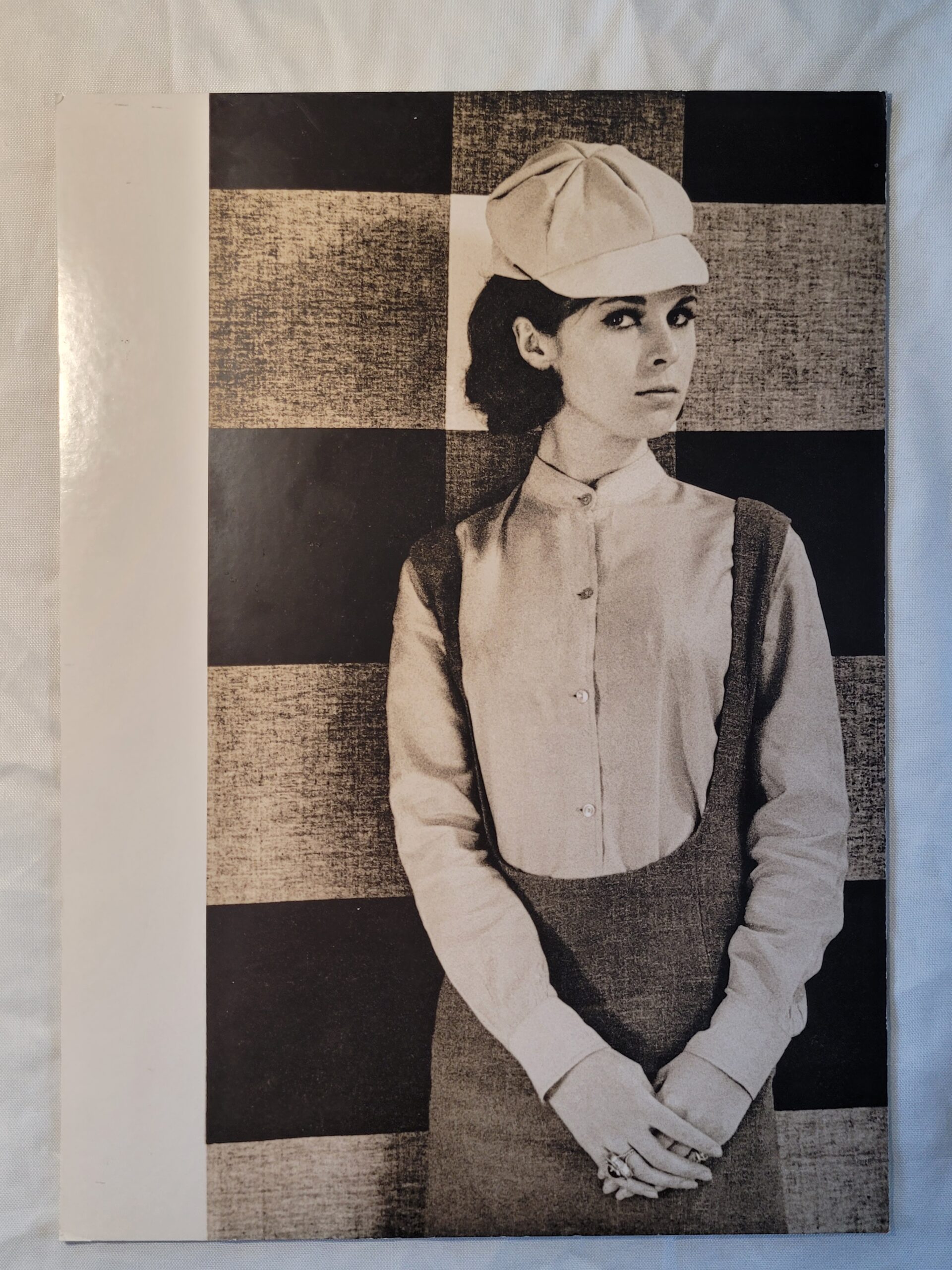Pretty brunette with hat in front of geometric wallpaper, by Michael Joseph