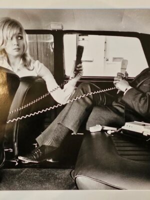 Couple with their carphones, carefree in a back of the car in the sixties by Michael Joseph