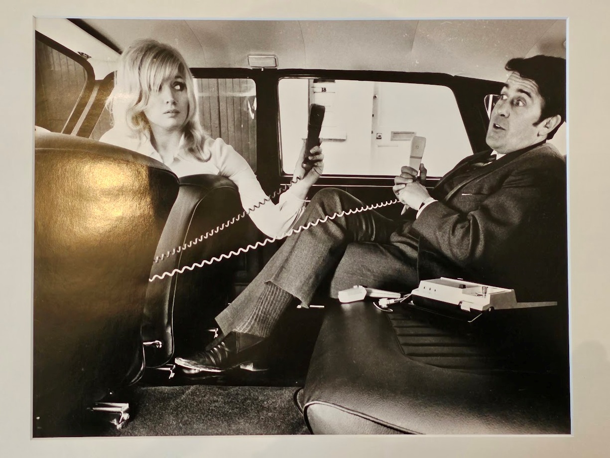 Couple with their carphones, carefree in a back of the car in the sixties by Michael Joseph