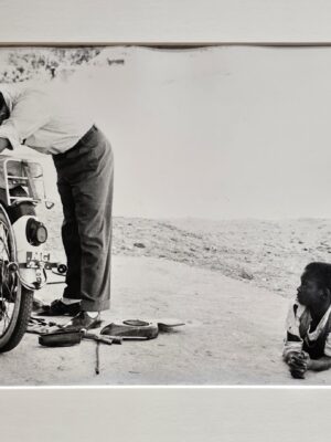 Child lying on floor watching motorbike reparation by Michael Joseph