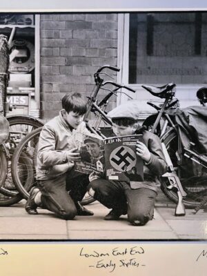 Boys reading Nazi magazine in East End London, kneeling on the pavement in the sixties by Michael Joseph