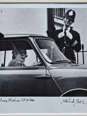 Dame agée au volant d'une Mini Cooper avec un gendarme à côté, photo prise à Londres par Michael Joseph