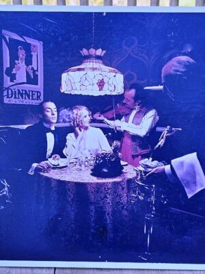 Colour print of fiddler and couple dining for UK Shell Mex and BP oil-fired central heating ad by Michael Joseph