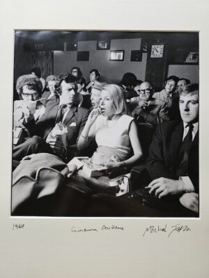 Femme des années 60 en train de manger au cinéma, avec son voisin visiblement agacé – les émotions à leur comble