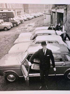 Concessionnaire automobile sur le parvis avec chapeau melon, tirage d'essai authentique en chambre noire